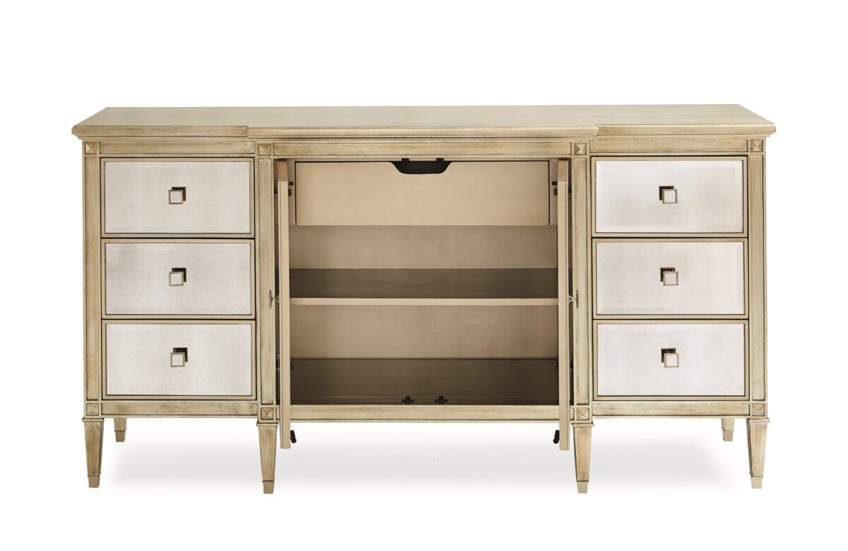 La‑Dee‑Dah Dresser by Caracole — a 74″‑wide carved dresser with six soft‑close side drawers and two mirrored center doors, finished in Auric silver leaf with beveled antique-mirror fronts, square tapered carved feet with metal ferrules, and a gold-painted interior featuring a tray drawer and shelf.