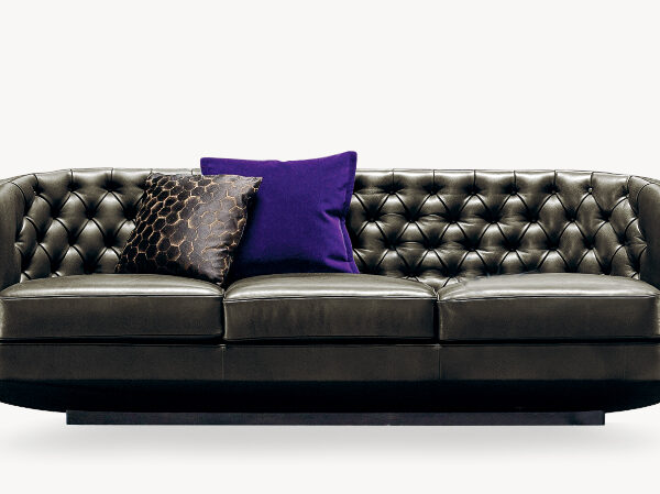Side view of the Rich Cushion sofa by Moroso, showcasing its elegant tufted backrest and sleek wooden legs.