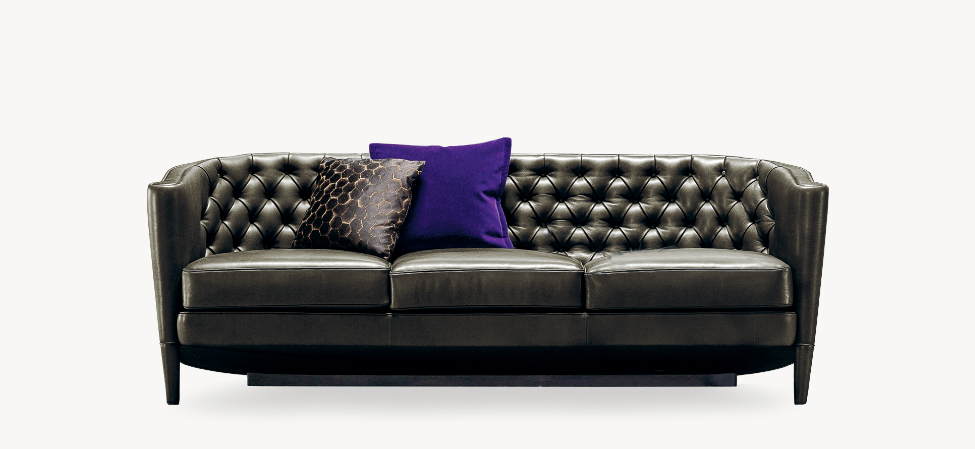 Side view of the Rich Cushion sofa by Moroso, showcasing its elegant tufted backrest and sleek wooden legs.