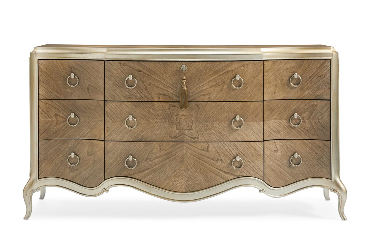 Fontainebleau triple dresser by Caracole — a serpentine‑front dresser with nine drawers crafted from Cendre-finished flat-cut walnut and trimmed in Champagne Mist, featuring carved cabriole legs, custom ring pulls with vintage cameo details, and a softly scalloped silhouette.