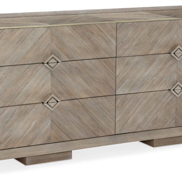 Naturally Dresser by Caracole — a 74″‑wide six‑drawer dresser in Ash Driftwood finish with chevron‑patterned wood‑veneer fronts, accented by a slender Sundance Gold metal bead edging and recessed drawer pulls, all sitting on low block feet.