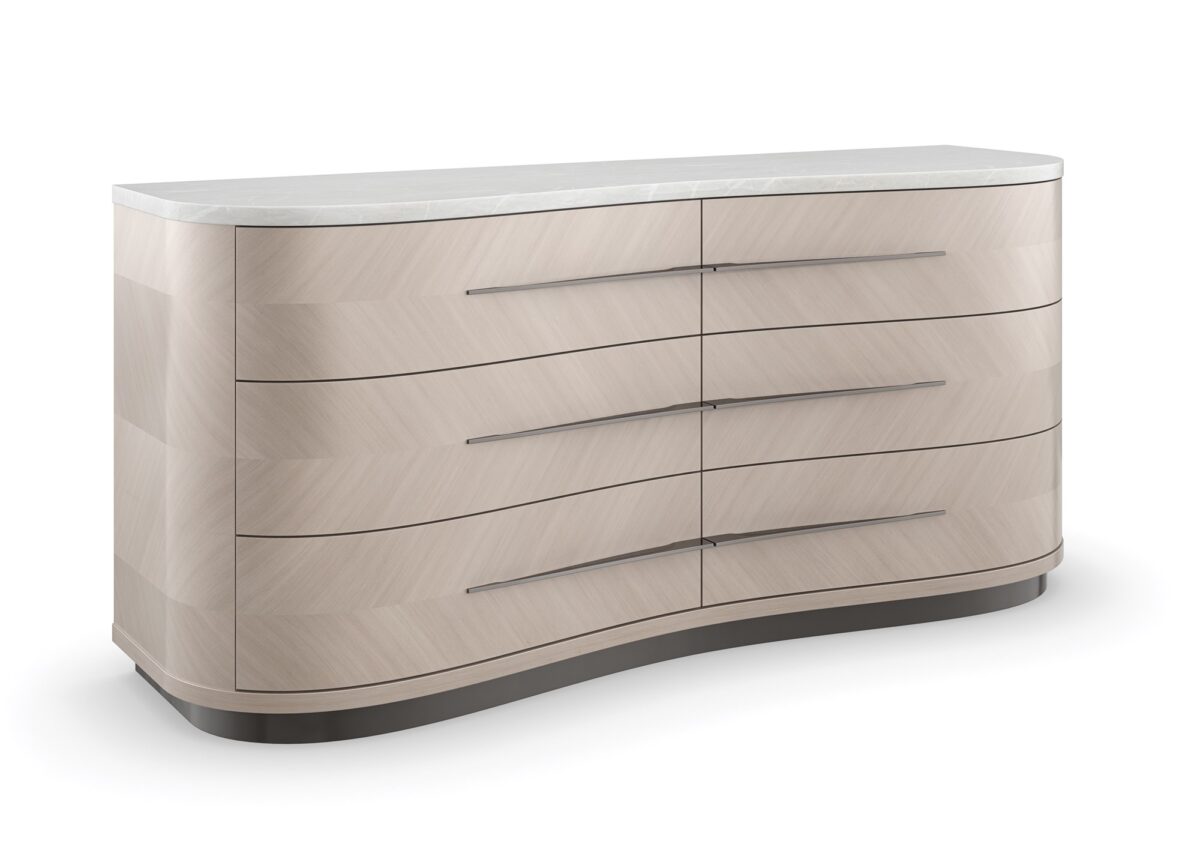 Roam Dresser by Caracole — a sleek 68″‑wide dresser in pearlescent Moonstone finish with six gently curved soft‑close drawers featuring horizontal Deep Bronze handles; chevron‑patterned Koto veneers flow organically across the fronts and end panels, topped with luxurious white Rhino marble and set atop a Seal‑Skin tone plinth base.