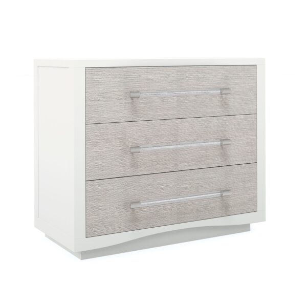 A Clear Touch chest by Caracole — a 38″‑wide three‑drawer chest in Pearly White textured finish, with sun‑kissed silver raffia-wrapped drawer fronts, clear acrylic rod pulls capped in satin nickel, undermount soft‑close guides, and painted pearly-white drawer interiors.