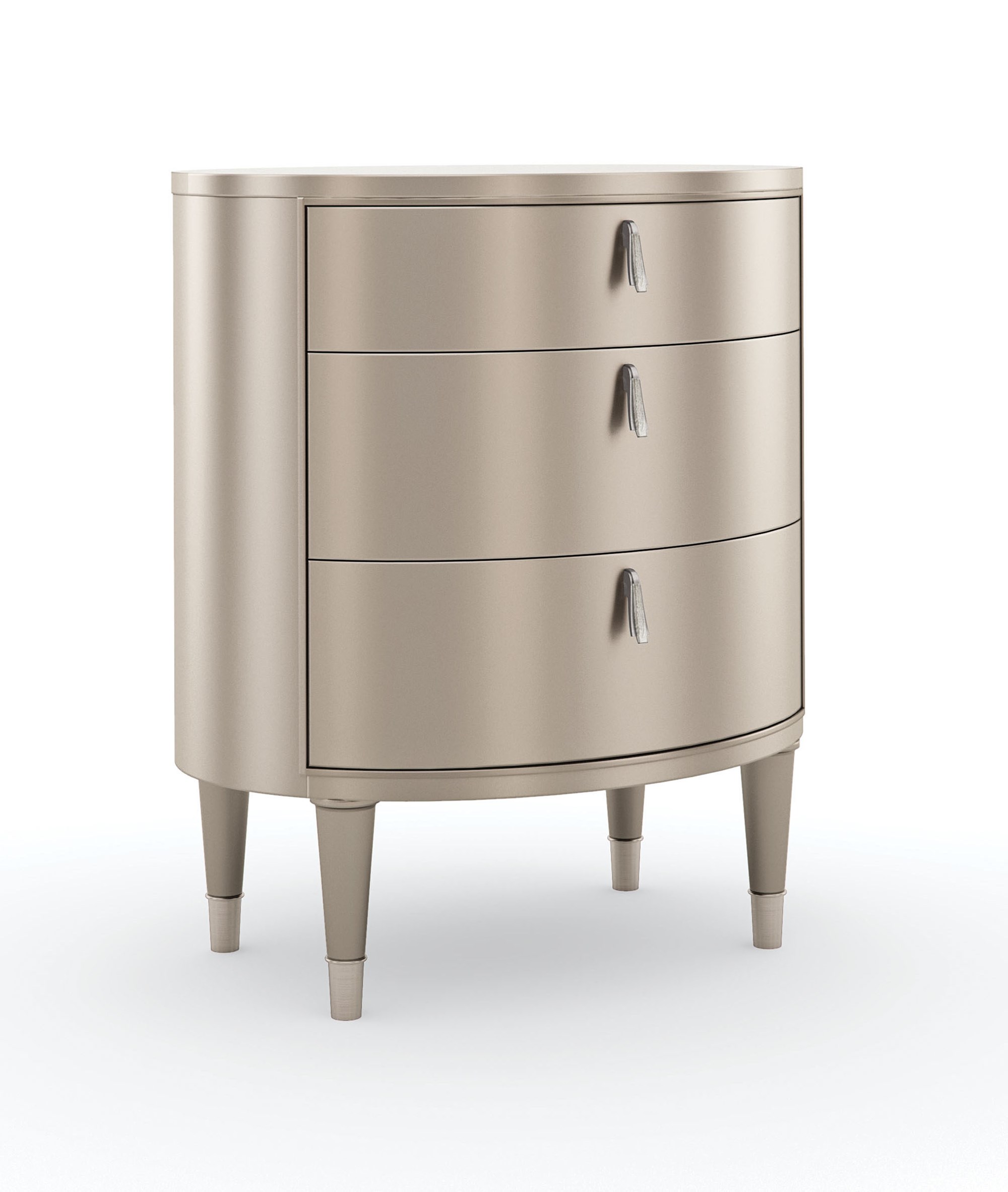 Bedside Beauty Nightstand by Caracole — a 24″-wide oval nightstand with three soft‑close drawers, finished in shimmering soft‑silver paint on Asian hardwood, topped with a softly curved top, accented by polished stainless‑steel ferrules on tapered legs, and elongated Art‑Deco pendant-style drawer pulls with faux-stone centers.