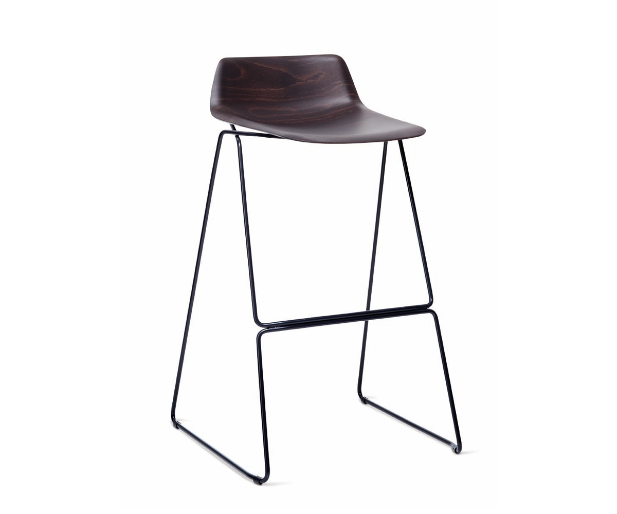 Pressious Stool by Casamania & Horm – Designed by Harry & Camila, featuring a sculptural beech plywood seat shaped using advanced 3D technology, complemented by a black painted metal sled base, suitable for both residential and commercial spaces.