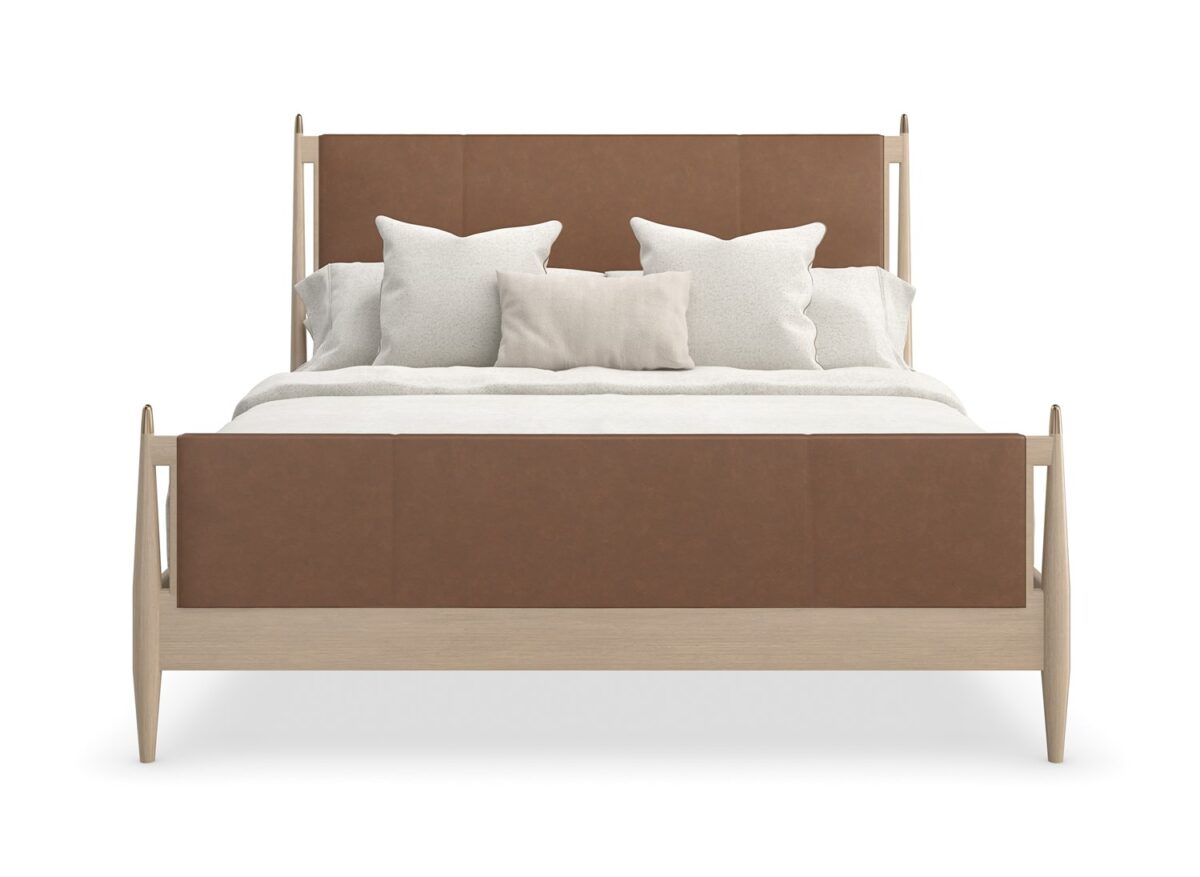 Caracole Rhythm King Bed featuring a luxurious camel-colored leather upholstered headboard and footboard, complemented by a Sun Drenched Oak wood frame with metal finials in Lucent Bronze finish, designed with clean, parsons-style lines.
