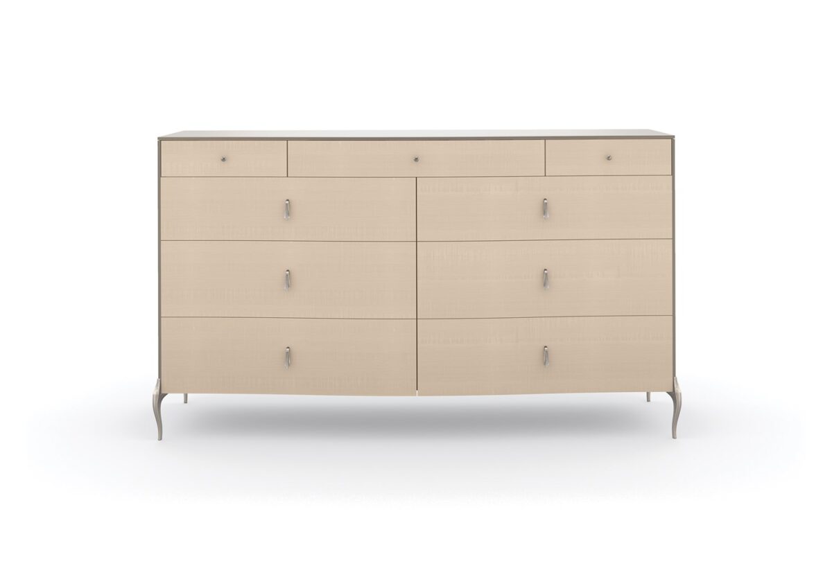 Dress to Impress Dresser by Caracole — a 62″ wide nine‑drawer dresser in soft‑silver painted Asian hardwood case, with vanilla‑cream figured‑sycamore drawer fronts, elongated Art‑Deco style metal pulls, a gently curved top, ornate silver‑toned legs, and two felt‑lined top drawers.