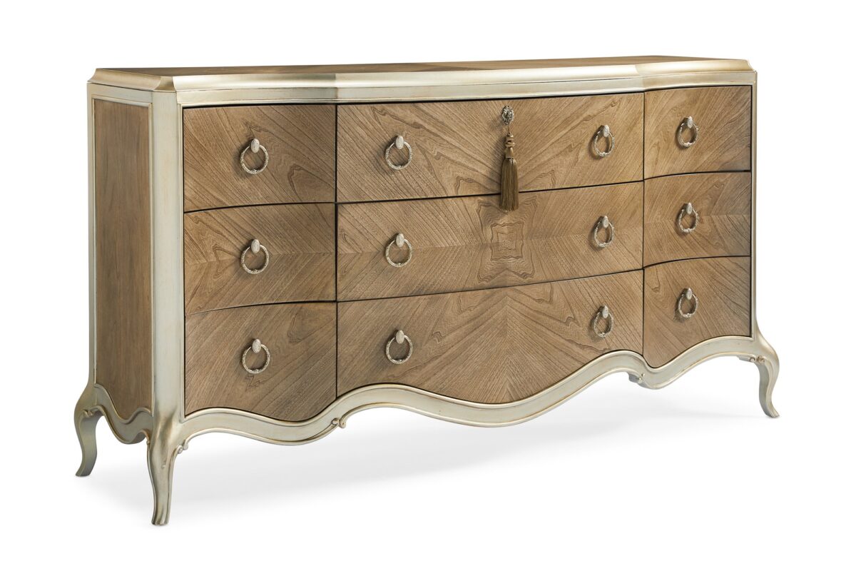 Fontainebleau triple dresser by Caracole — a serpentine‑front dresser with nine drawers crafted from Cendre-finished flat-cut walnut and trimmed in Champagne Mist, featuring carved cabriole legs, custom ring pulls with vintage cameo details, and a softly scalloped silhouette.