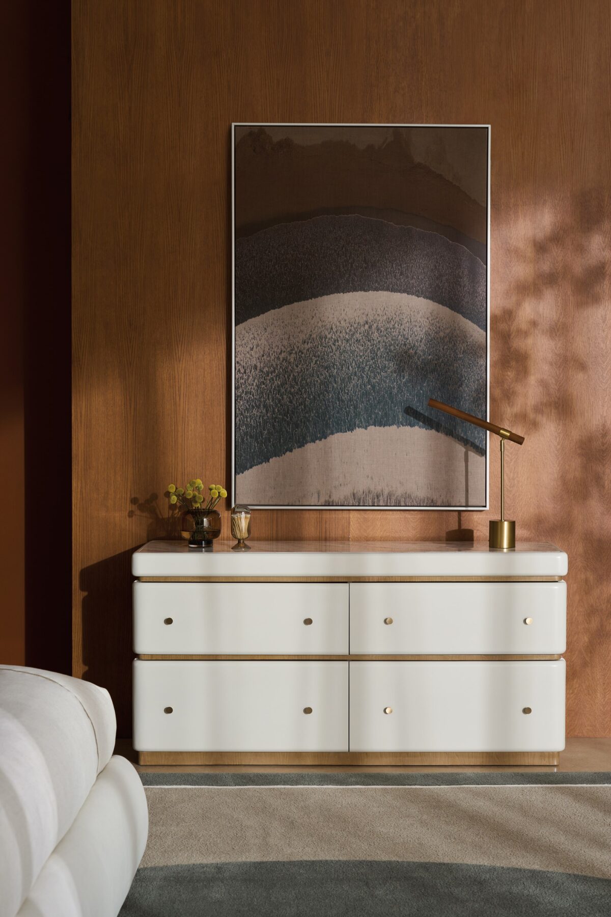 Milos Dresser by Caracole — a 65″‑wide modern dresser in Almond Milk finish with gently rounded stacked silhouette, featuring four soft‑close drawers trimmed in Toasted Pecan, topped with Calacatta Oro marble, and equipped with a removable felt‑lined tray in the top drawer.