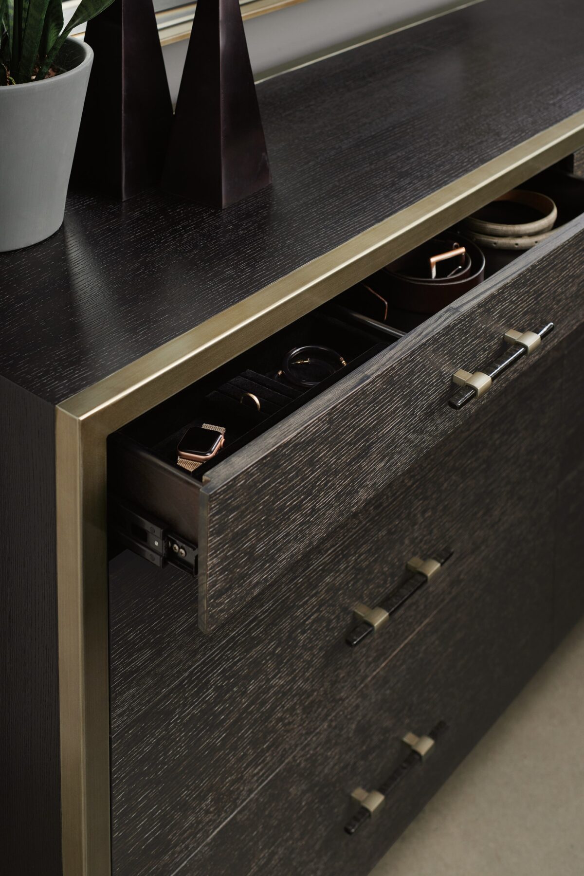 ReMix Double Dresser by Caracole — a 66″‑wide double dresser with eight soft‑close drawers; case and interior in black‑stained ash, drawer fronts in cerused oak, accented with a slim bronze‑gold metal frame and matching bronze‑painted trim, including a top‑left drawer with removable dividers.