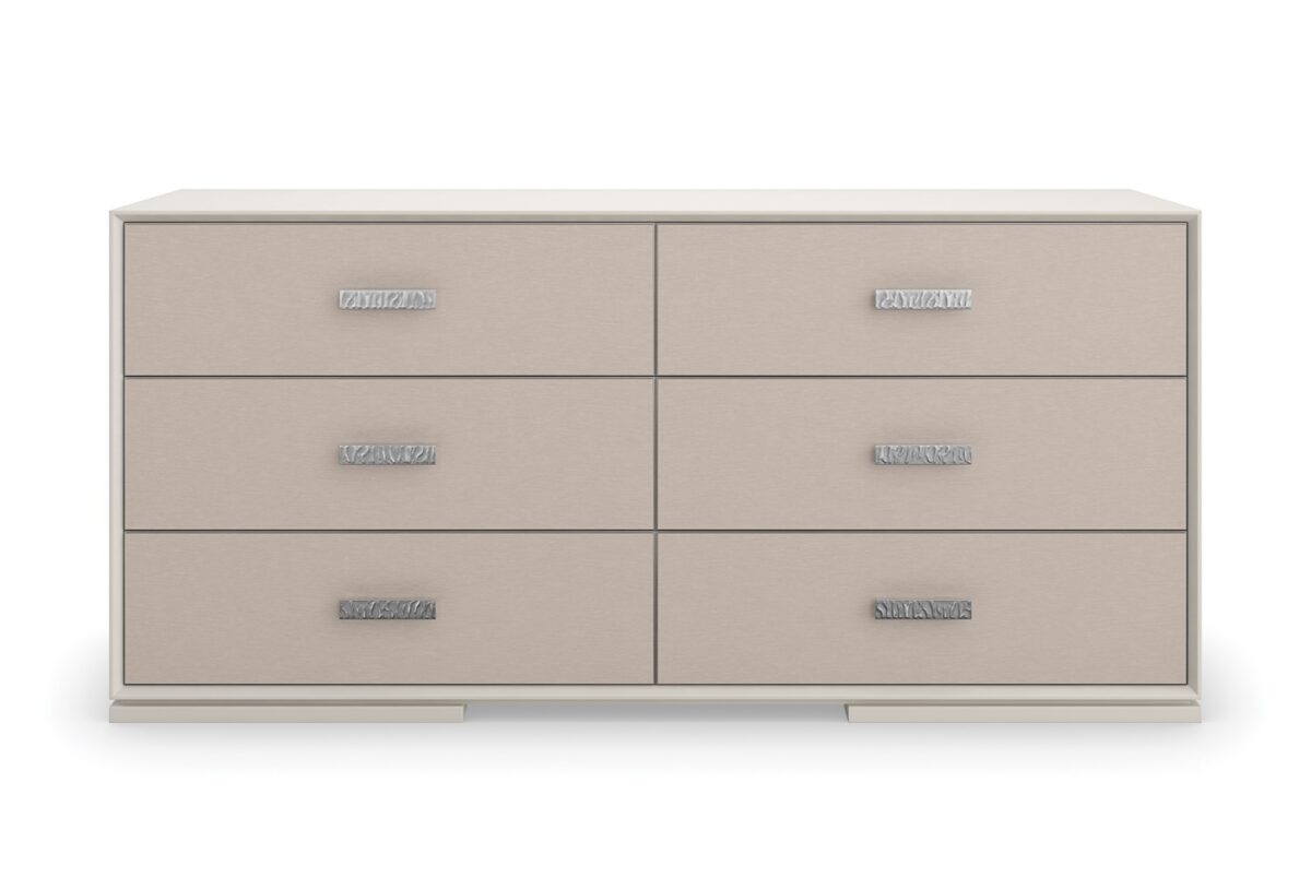 Silver Lining Dresser by Caracole — a 68″‑wide six‑drawer classic dresser in Almond Milk lacquer finish, featuring vinyl-wrapped drawer fronts with a soft blush Venetian silk hue, undulating brushed stainless-steel custom handles, recessed metal trim, soft‑close undermount guides, and UV‑lined linen interiors.