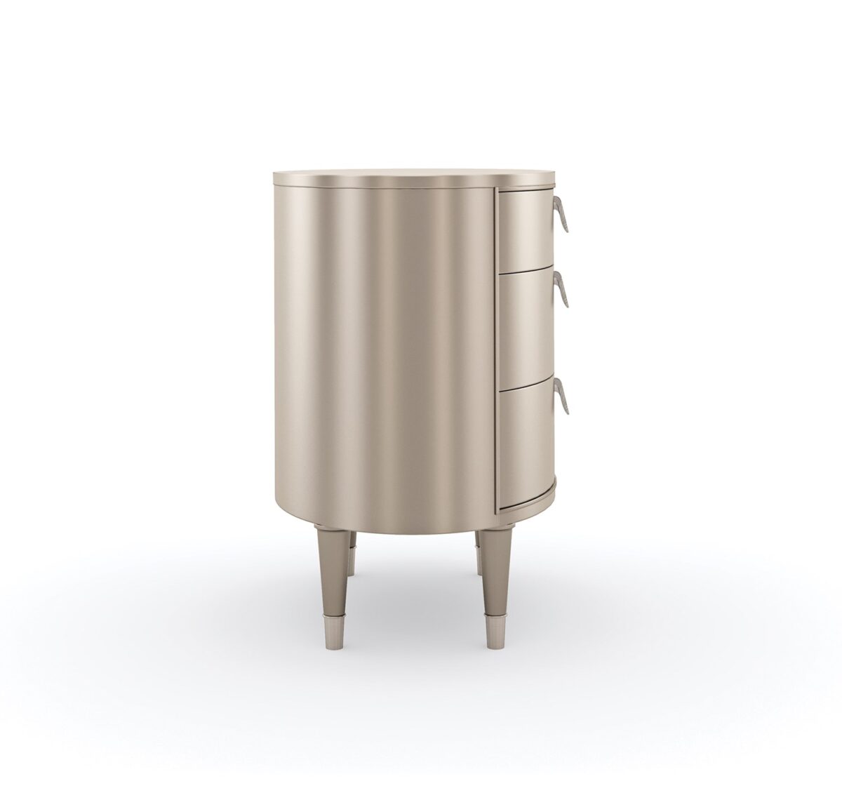 Bedside Beauty Nightstand by Caracole — a 24″-wide oval nightstand with three soft‑close drawers, finished in shimmering soft‑silver paint on Asian hardwood, topped with a softly curved top, accented by polished stainless‑steel ferrules on tapered legs, and elongated Art‑Deco pendant-style drawer pulls with faux-stone centers.