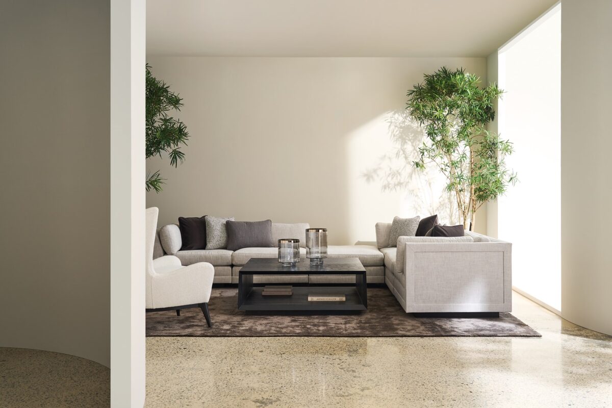 Caracole Fusion Armless Chair with neutral oatmeal tweed upholstery, a deep gunmetal grey accent pillow, and a recessed wood plinth base in Simply Black.