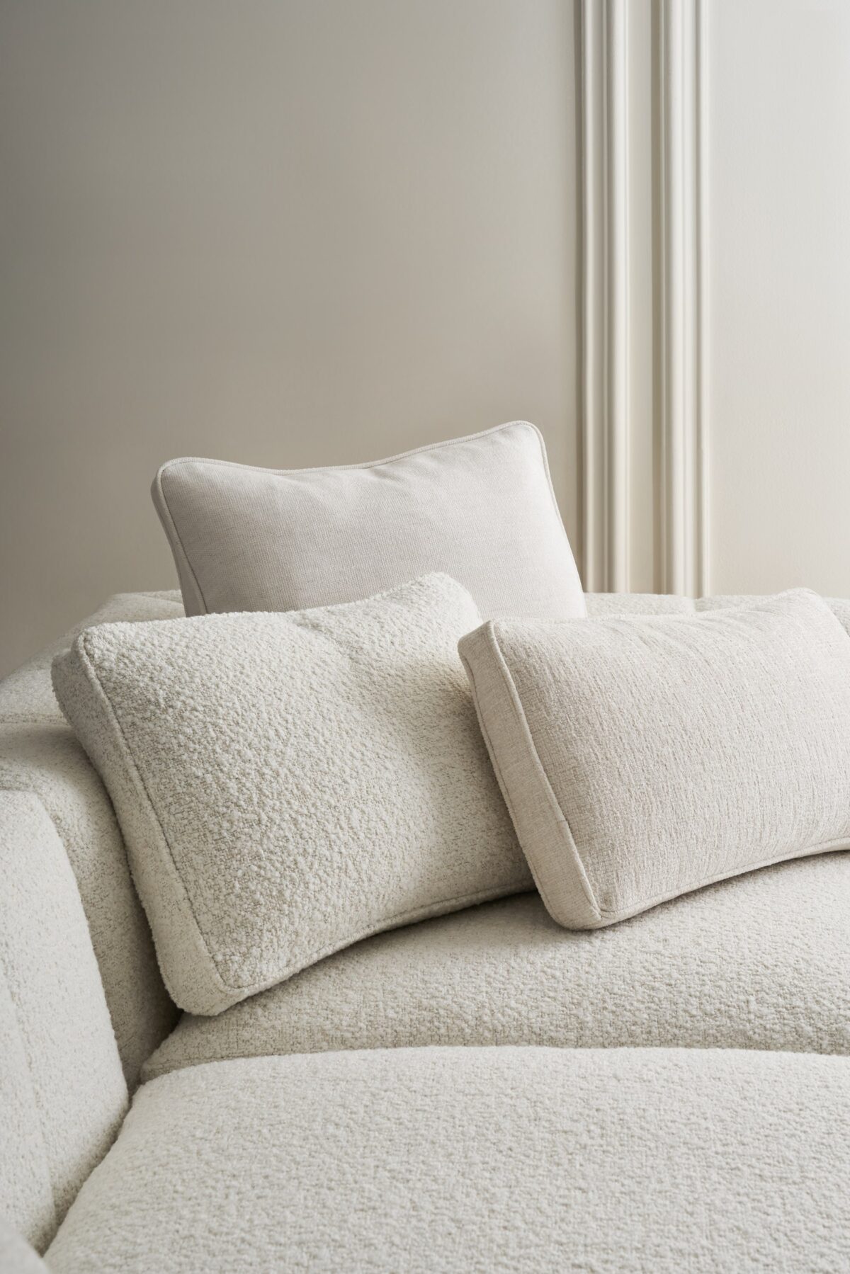 Caracole Fret Knot Corner featuring a carved fret panel inspired by a narrow castle window, Soft Silver Paint finish, fluted conical legs, and a supportive eight-way hand-tied seat.