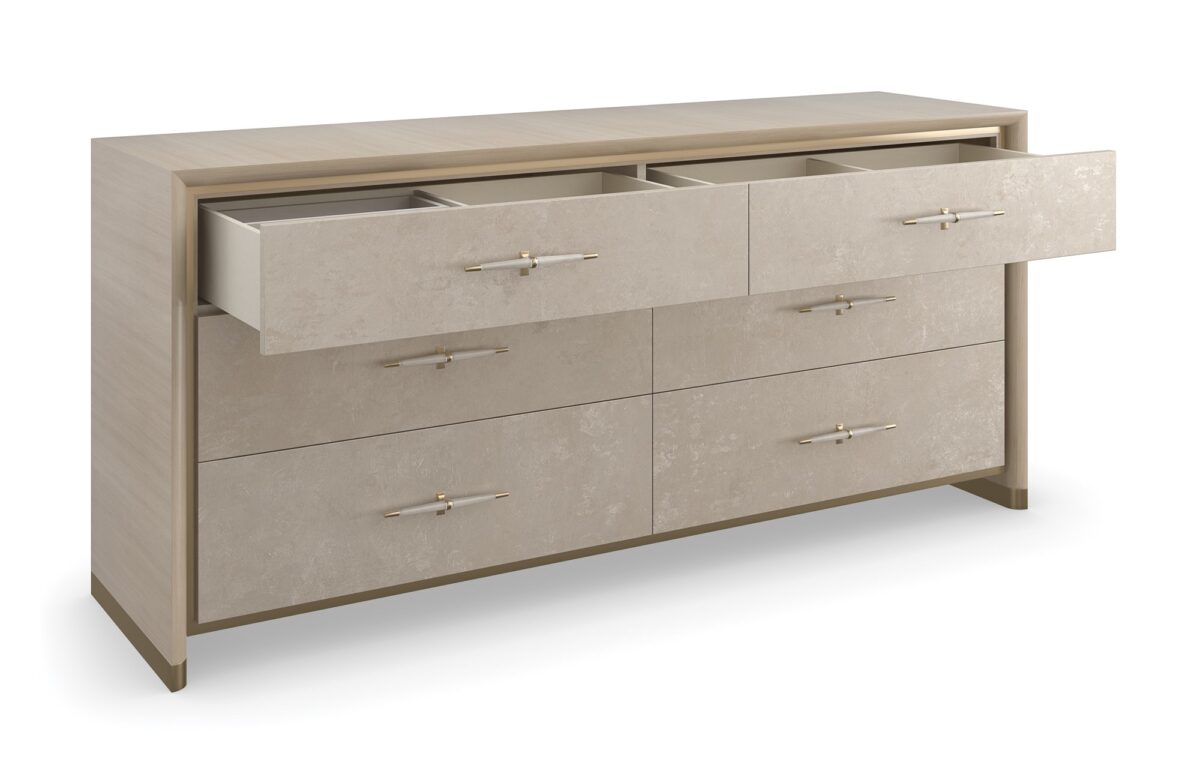 Hang Up Dresser by Caracole — a 70‑inch wide classic dresser with six drawers featuring metallic leaf-finish fronts that shimmer like frosted glass, set in a Dry Martini-finished hardwood frame with recessed metal trim, tapered faux‑leather-wrapped pulls in brushed gold and nickel, soft‑close drawers, and linen-painted interior with top drawer dividers and a removable jewelry tray.