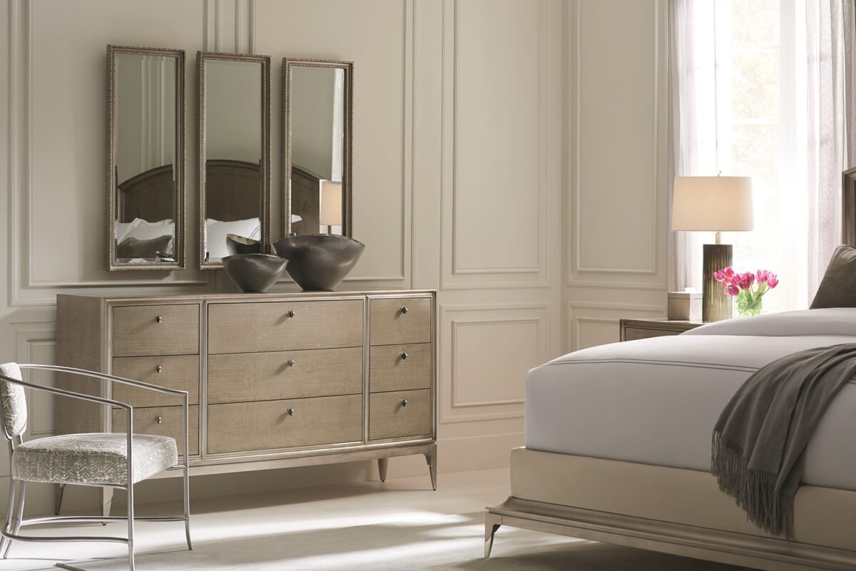 Made To Shine Dresser by Caracole — a 72″ wide nine-drawer dresser in Moonlit Sand–finished curly maple, accented with Soft Silver Leaf trim on the frame and base, topped by lightly brushed chrome metal ferrules on tapered legs, featuring antique silver knobs with black mother-of-pearl centers and soft-close undermount drawer guides.