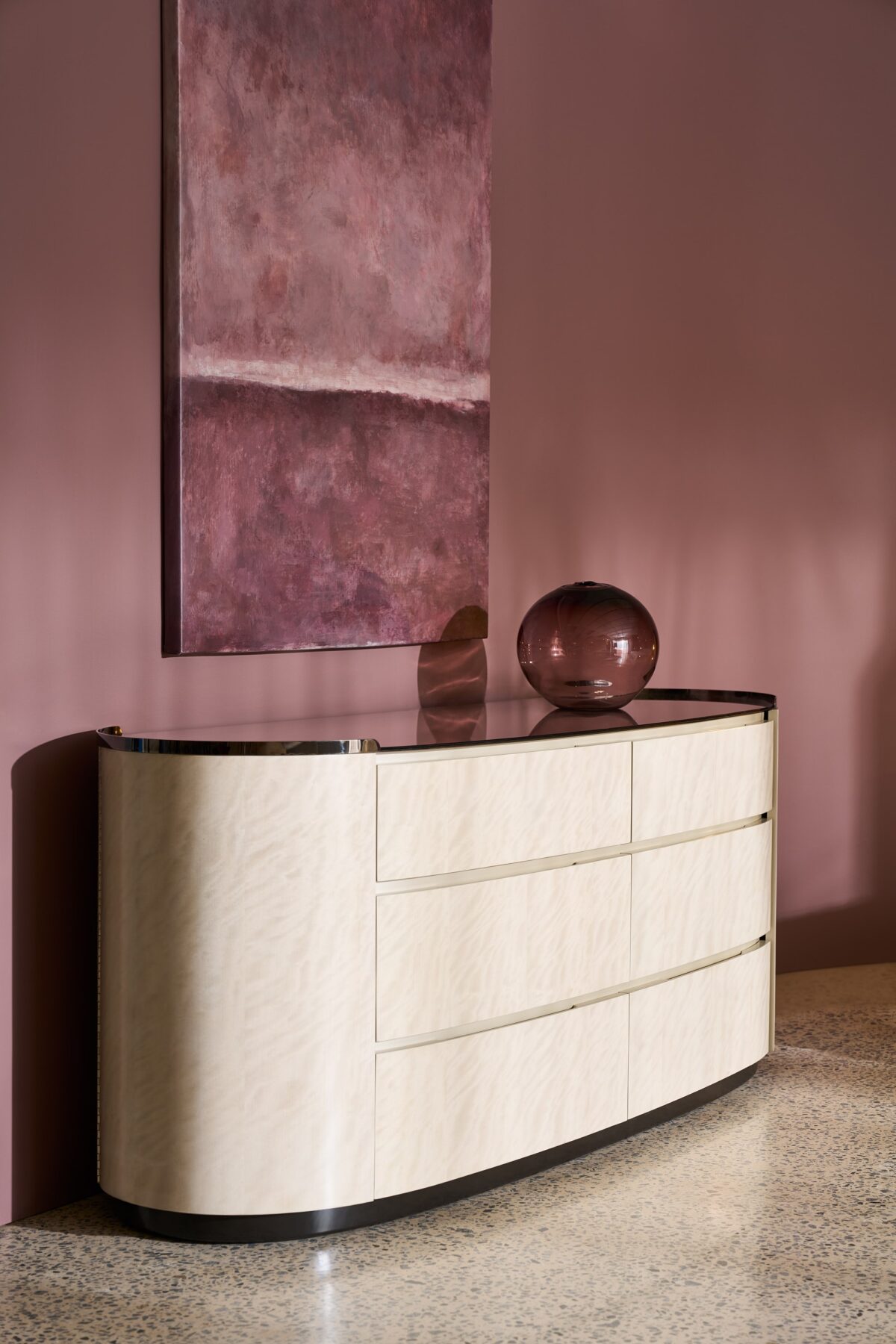 Muse Dresser by Caracole — a 79½″‑wide oval double dresser combining Nebulous‑finish Curupixa wood with a Dark Chocolate base, featuring six softly curved soft‑close drawers with grooved finger pulls, two end‑panel doors concealing jewelry and tie storage, topped with a Smoked Bronze mirrored surface framed in Deep Bronze metal.