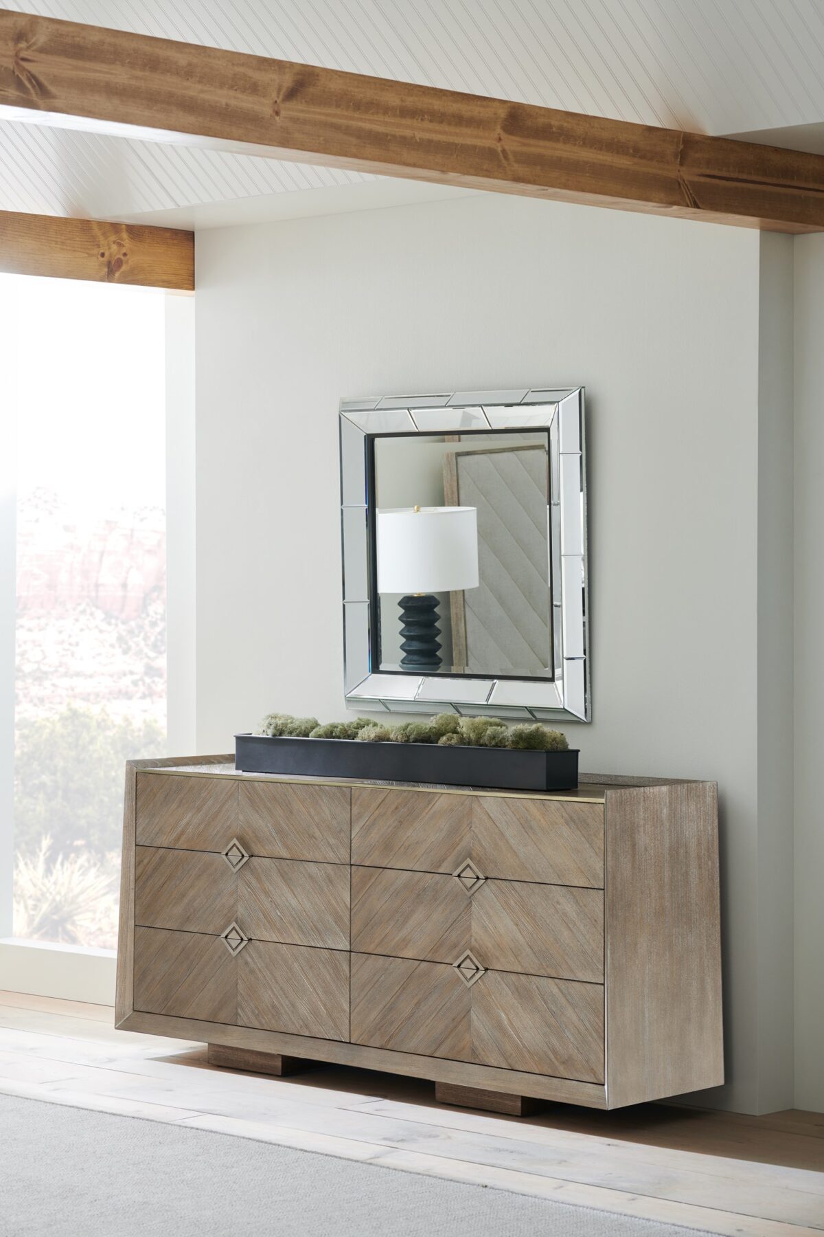 Naturally Dresser by Caracole — a 74″‑wide six‑drawer dresser in Ash Driftwood finish with chevron‑patterned wood‑veneer fronts, accented by a slender Sundance Gold metal bead edging and recessed drawer pulls, all sitting on low block feet.