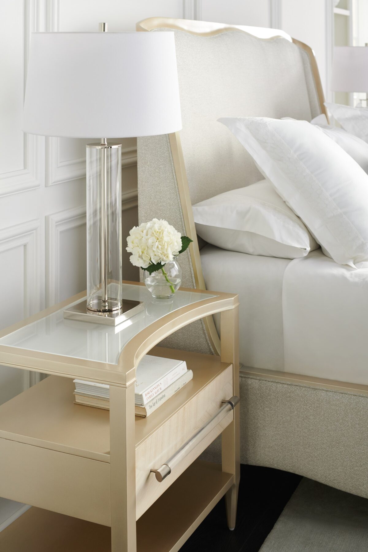 Clearly Open Nightstand by Caracole — a 24″‑wide modern nightstand featuring a frosted glass top with a crescent-shaped curve, supported by a Champagne Pearl–finished base. It includes a single soft-close drawer with a Natural Glow wood front, open storage above and below, and a clear acrylic pull rod capped in Satin Nickel.