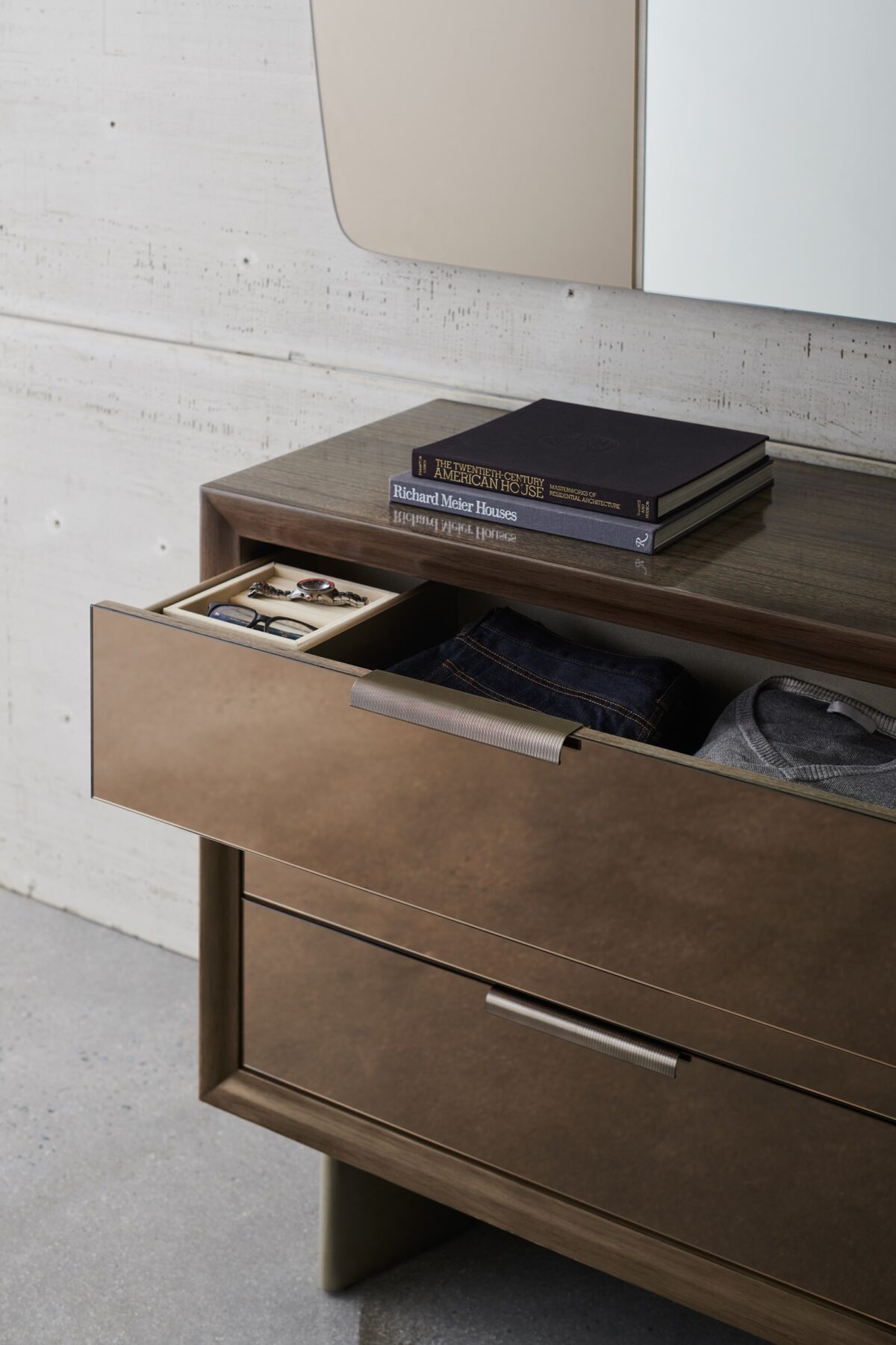 Fashion Dresser by Caracole — a curving six-drawer dresser in lustrous gold-leaf finish, topped with a mirrored bronze surface and slender tapered legs; each drawer features jewelry-like ring pulls and undermount soft-close operation.
