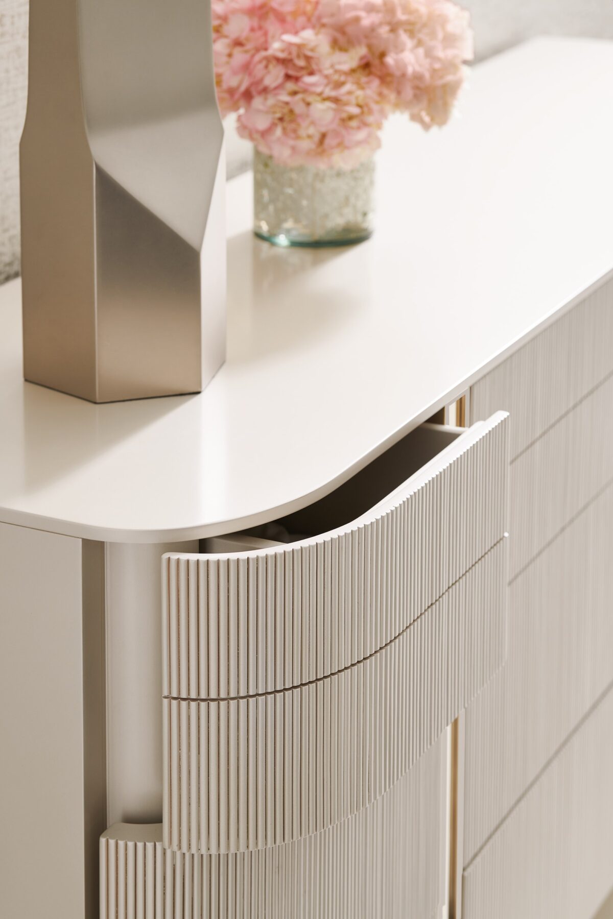 Love at First Sight Dresser by Caracole — a 74″‑wide curved‑front dresser in Matte Pearl finish with nine touch‑latch, reeded drawer fronts, soft‑close undermount guides, and Whisper‑of‑Gold metal legs and band accents.