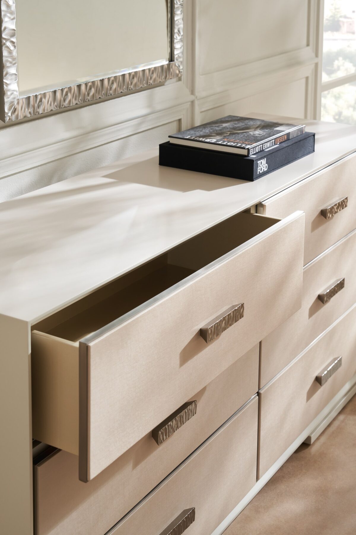 Silver Lining Dresser by Caracole — a 68″‑wide six‑drawer classic dresser in Almond Milk lacquer finish, featuring vinyl-wrapped drawer fronts with a soft blush Venetian silk hue, undulating brushed stainless-steel custom handles, recessed metal trim, soft‑close undermount guides, and UV‑lined linen interiors.