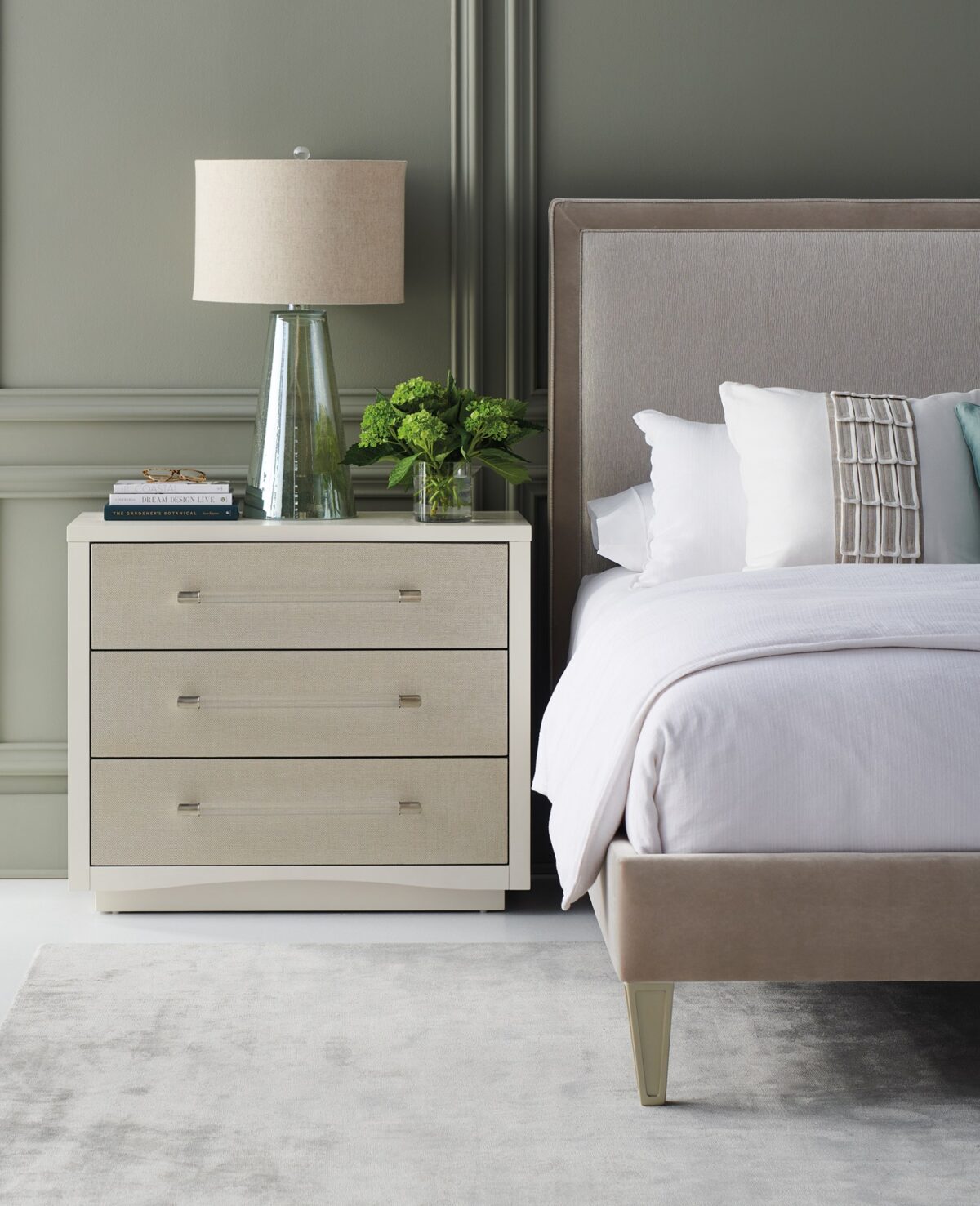 A Clear Touch chest by Caracole — a 38″‑wide three‑drawer chest in Pearly White textured finish, with sun‑kissed silver raffia-wrapped drawer fronts, clear acrylic rod pulls capped in satin nickel, undermount soft‑close guides, and painted pearly-white drawer interiors.
