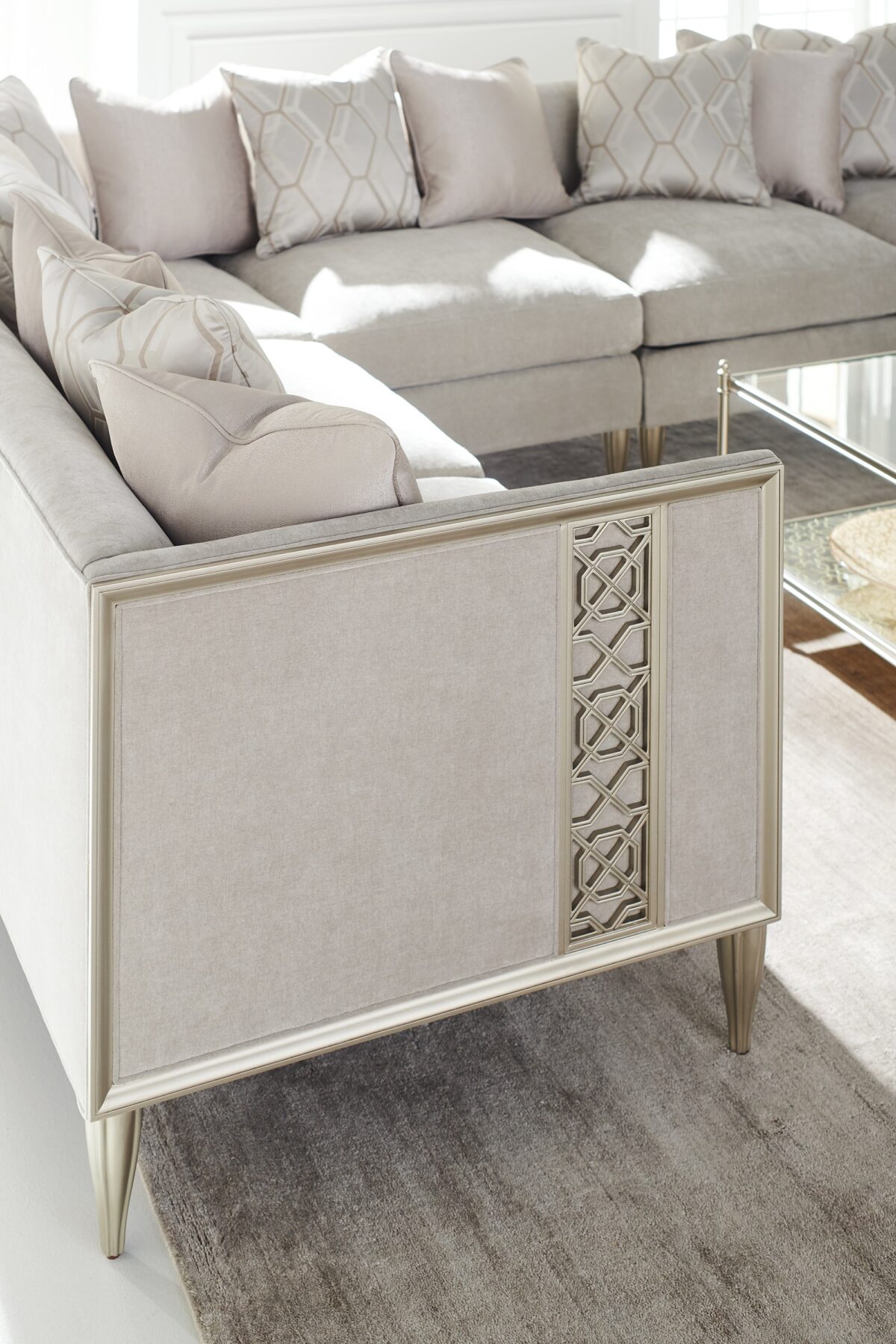 Caracole Fret Knot Corner featuring a carved fret panel inspired by a narrow castle window, Soft Silver Paint finish, fluted conical legs, and a supportive eight-way hand-tied seat.