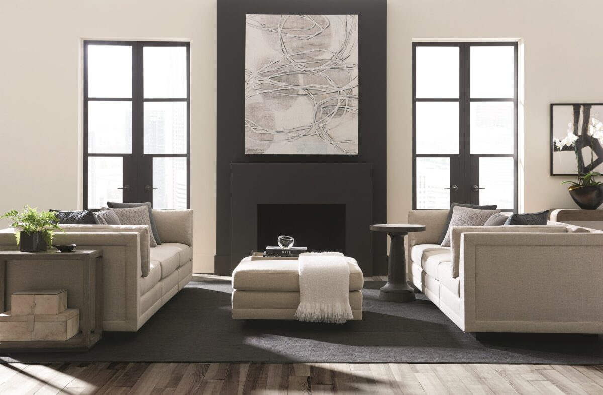 Caracole Fusion 3 Piece Sectional featuring a neutral, menswear-inspired textured tweed pattern, recessed Simply Black wood plinth base, cut-out frame detailing, and contrasting accent pillows in gunmetal velvet and black-and-white herringbone stitch.