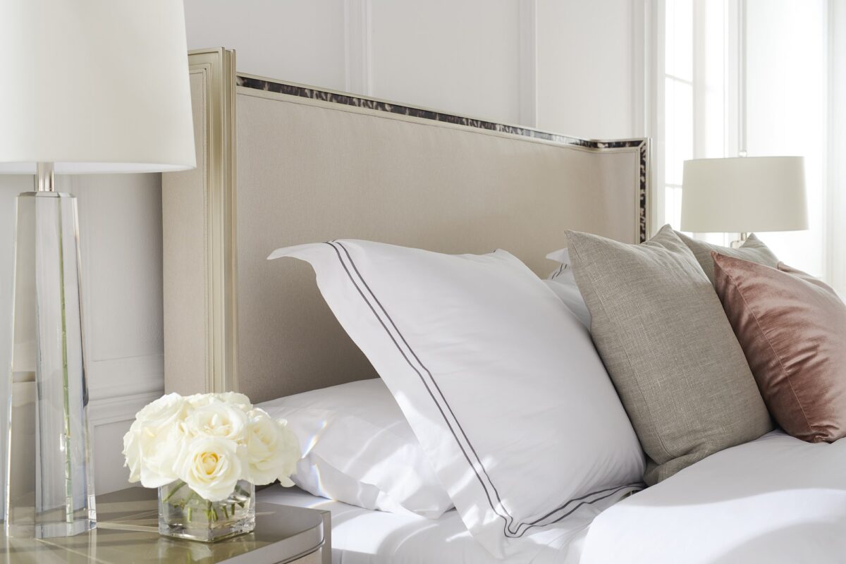 Caracole Dream Big California King Bed featuring a gently curving headboard with acrylic tortoise shell-inspired inlay, upholstered footboard and side rails in performance fabric, and a contemporary plinth base in Soft Silver Paint.
