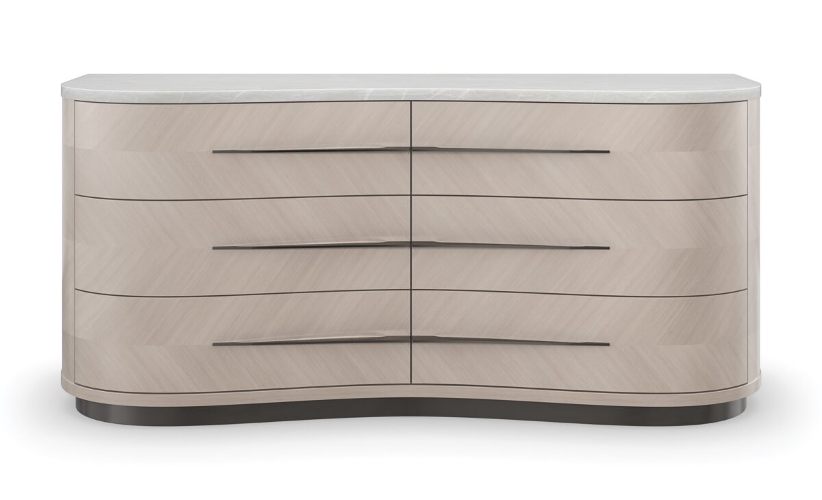 Silver Lining Dresser by Caracole — a 68″‑wide six‑drawer classic dresser in Almond Milk lacquer finish, featuring vinyl-wrapped drawer fronts with a soft blush Venetian silk hue, undulating brushed stainless-steel custom handles, recessed metal trim, soft‑close undermount guides, and UV‑lined linen interiors.