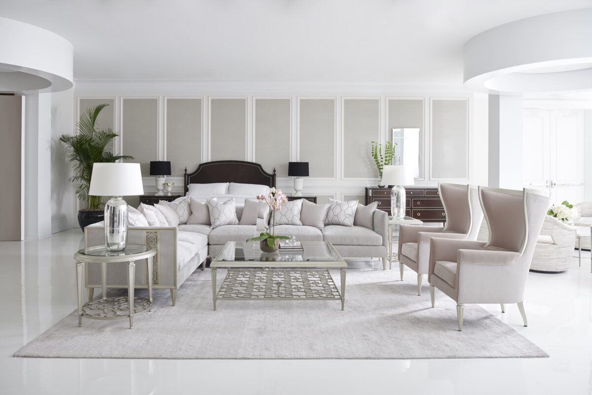 Caracole Fret Knot Corner featuring a carved fret panel inspired by a narrow castle window, Soft Silver Paint finish, fluted conical legs, and a supportive eight-way hand-tied seat.