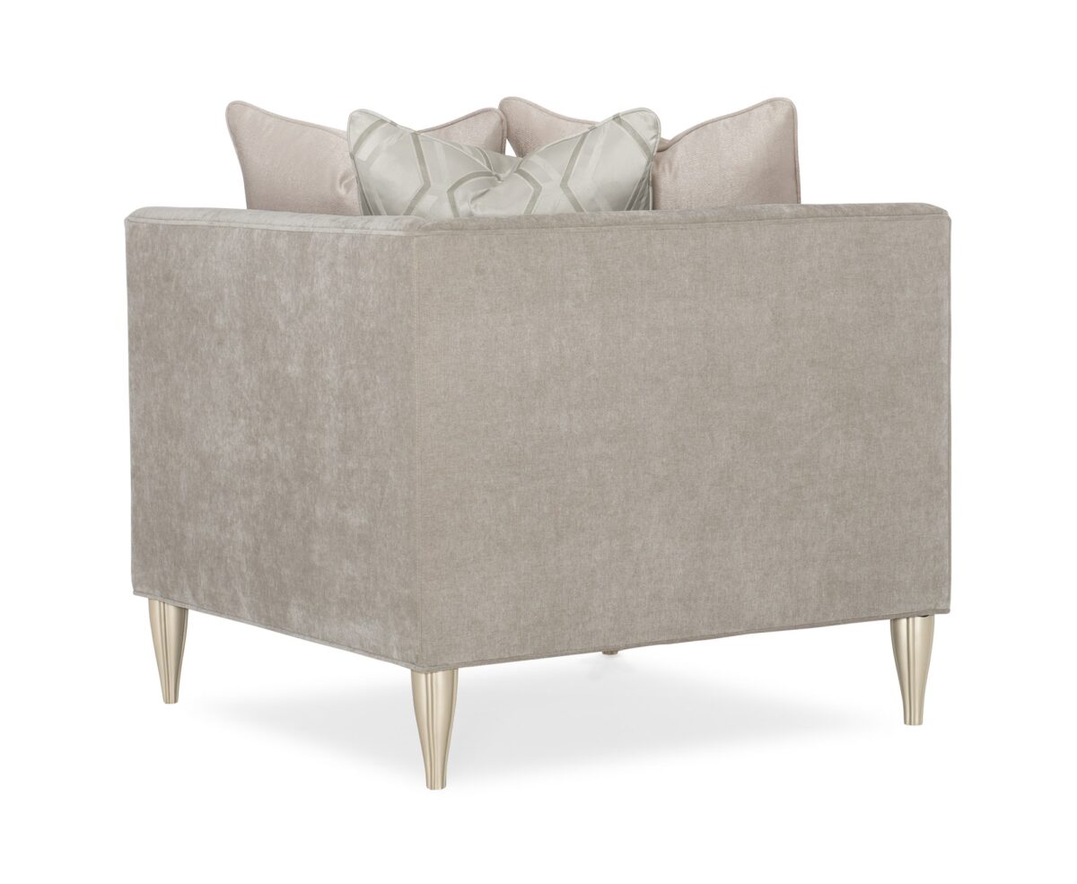 Caracole Fret Knot Corner featuring a carved fret panel inspired by a narrow castle window, Soft Silver Paint finish, fluted conical legs, and a supportive eight-way hand-tied seat.