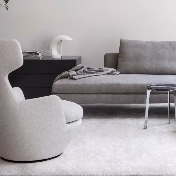 My Turn by Bensen swivel lounge chair in soft gray fabric with rounded backrest and black metal base in a contemporary living room