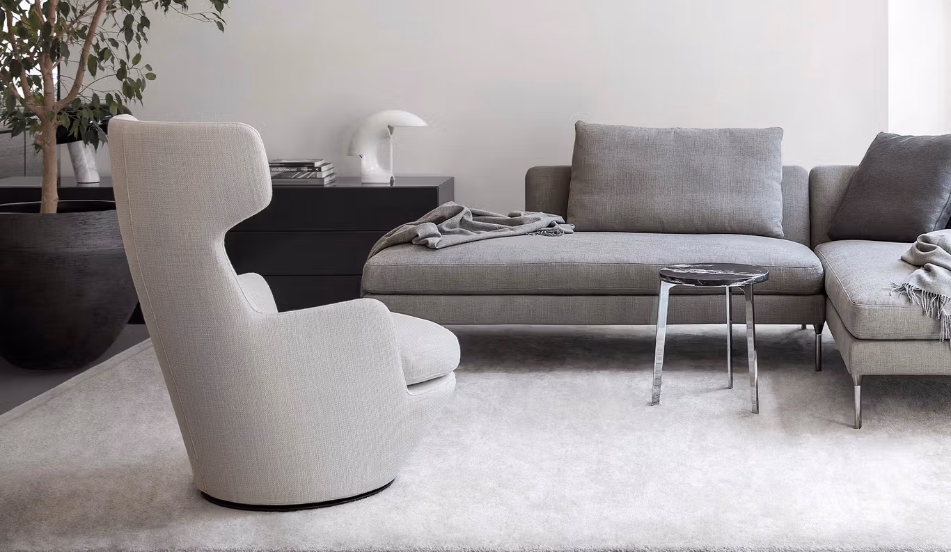 My Turn by Bensen swivel lounge chair in soft gray fabric with rounded backrest and black metal base in a contemporary living room