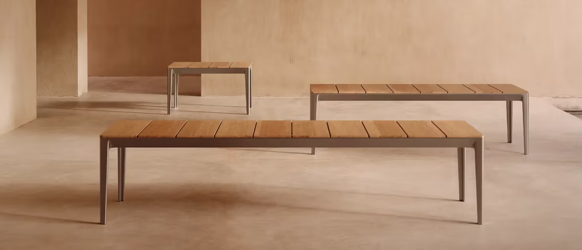 Outdoor Able Bench by Bensen in matte black aluminum set on a stone patio with garden backdrop