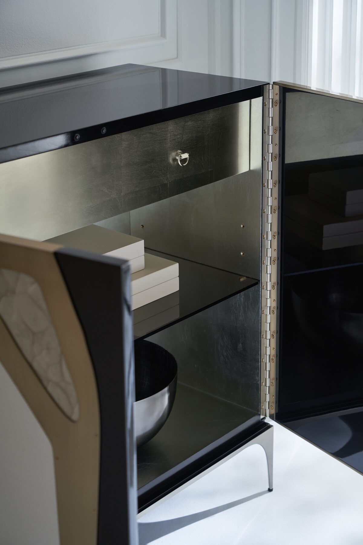 The Caracole "Downtown" bar cabinet, a luxurious and modern chest with door fronts framed in Chocolate Truffle lacquer, featuring a tactile mix of faux shagreen and Café Latte hand-printed resin with a Brushed Gold overlay, and resting on a Tungsten metal base.