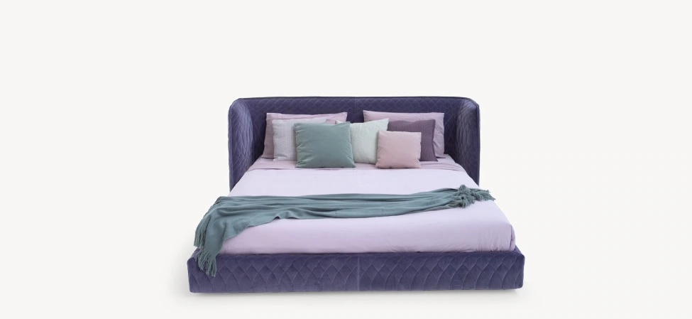 Redondo round bed by Moroso in quilted lilac fabric with enveloping curved headboard and low-profile base