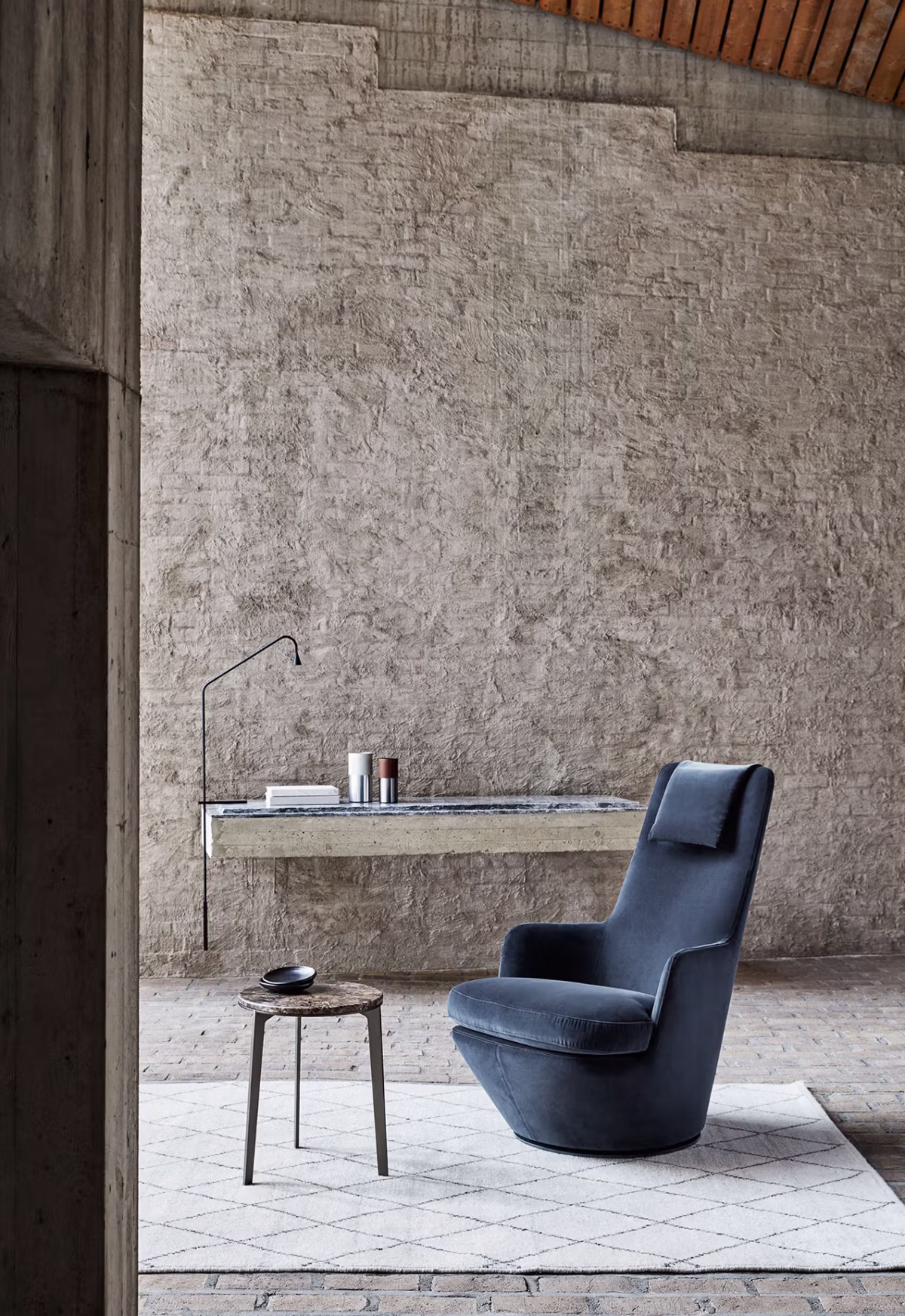 Hi Turn chair by Bensen in deep blue upholstery placed beside a floor lamp and small round side table