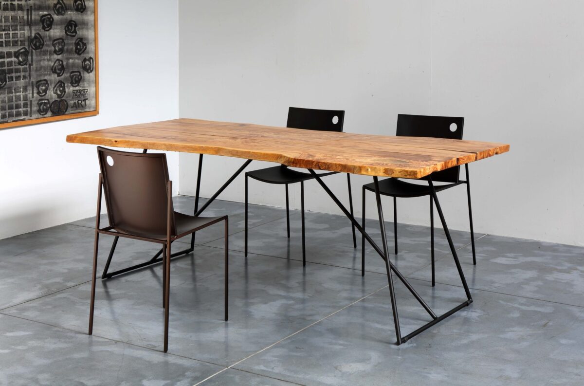 Close-up of AURORA Chair’s perforated metal backrest and curved tubular steel legs highlighting craftsmanship details.