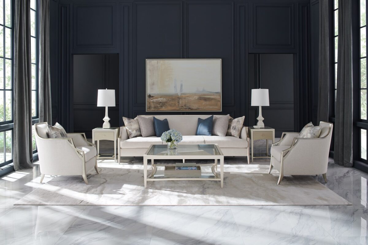 The Caracole X Factor Sofa, a modern classic upholstered in a herringbone performance fabric, featuring a wood-trimmed silhouette with a carved crisscross pattern, gently sloping arms, splayed legs in a metallic Charcoal Leaf finish, and feather-down toss pillows.