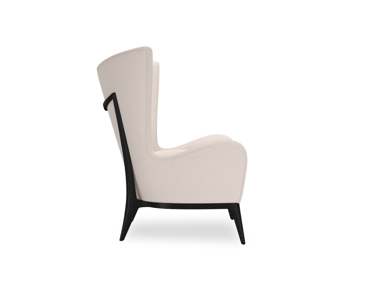 The Caracole "Whats New Pussycat?" wing chair, featuring a modern Scandinavian design with a light-colored upholstered body, gracefully sloped arms, a soft round back, and a distinctive exposed wood detail on the outback in a Modern Walnut or Almost Black finish.