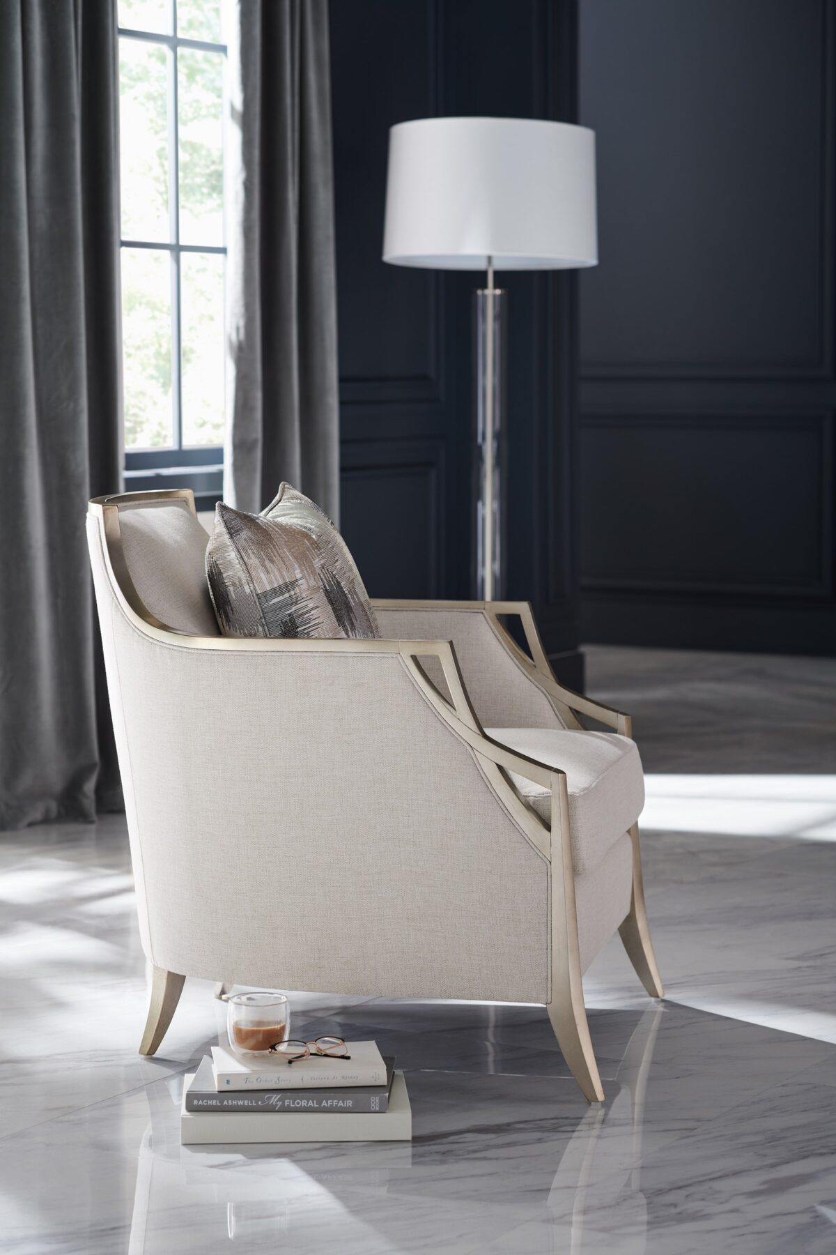 The Caracole X Factor Sofa, a modern classic upholstered in a herringbone performance fabric, featuring a wood-trimmed silhouette with a carved crisscross pattern, gently sloping arms, splayed legs in a metallic Charcoal Leaf finish, and feather-down toss pillows.