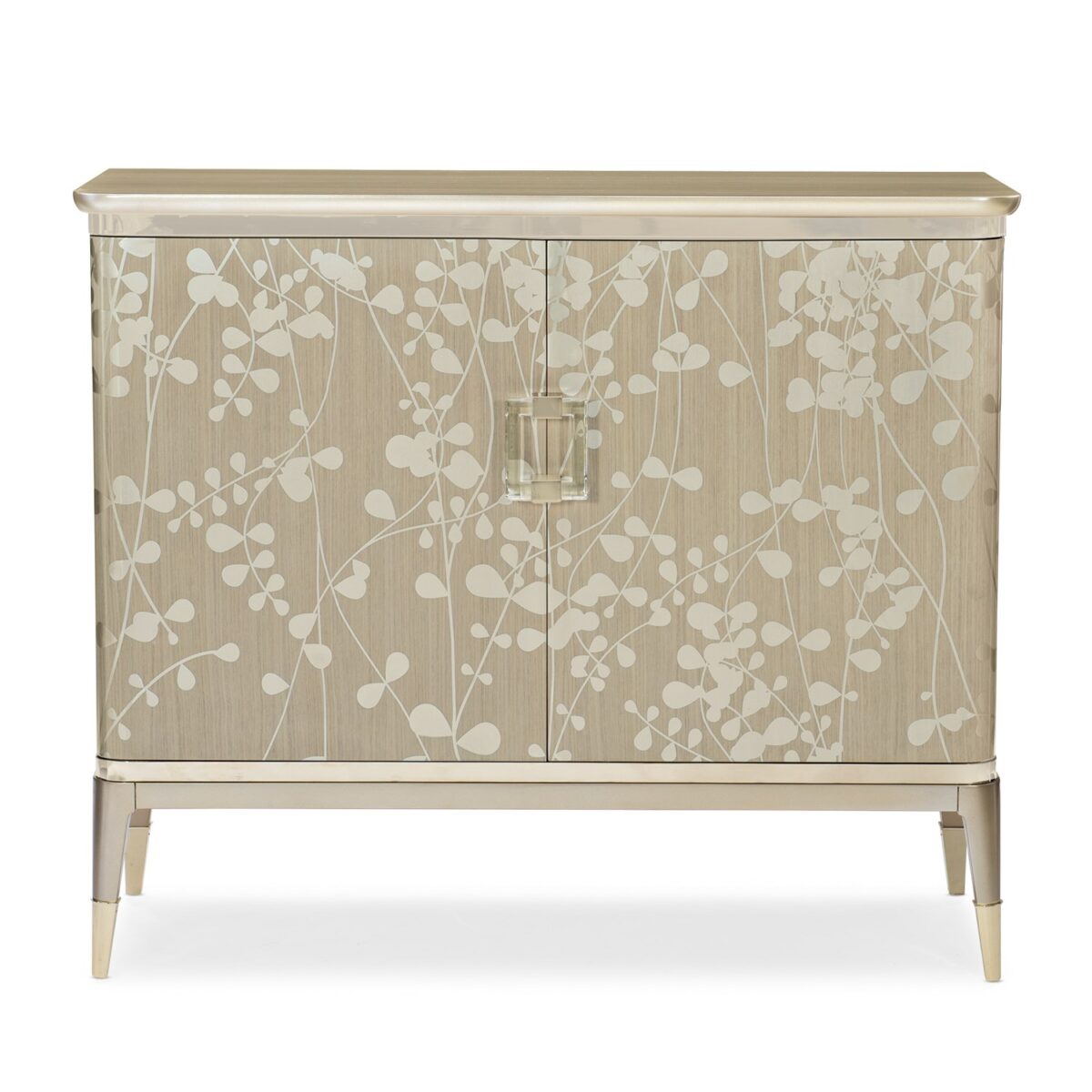 The Caracole "A Shimmer of Light" chest, a transitional storage piece with a shimmering Champagne Shimmer finish, a subtle silkscreened leaf pattern in Taupe, and elegant plated Whisper of Gold trim, ferrules, and hardware.