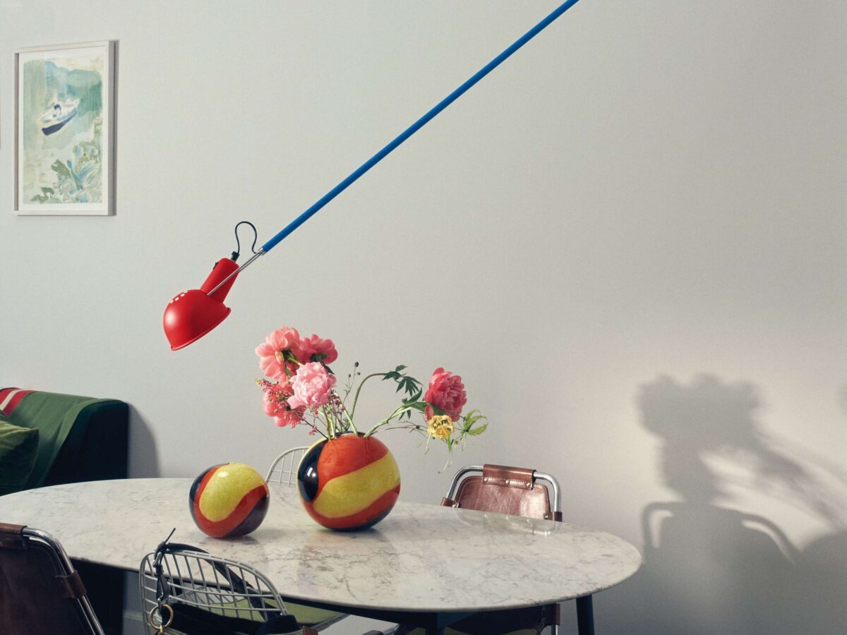 Architectural wall lamp, the Flos 265 Chromatica, showcasing its functional elements with bold primary colors: red for the reflector, blue for the extended arm, and yellow for the balancing counterweight.