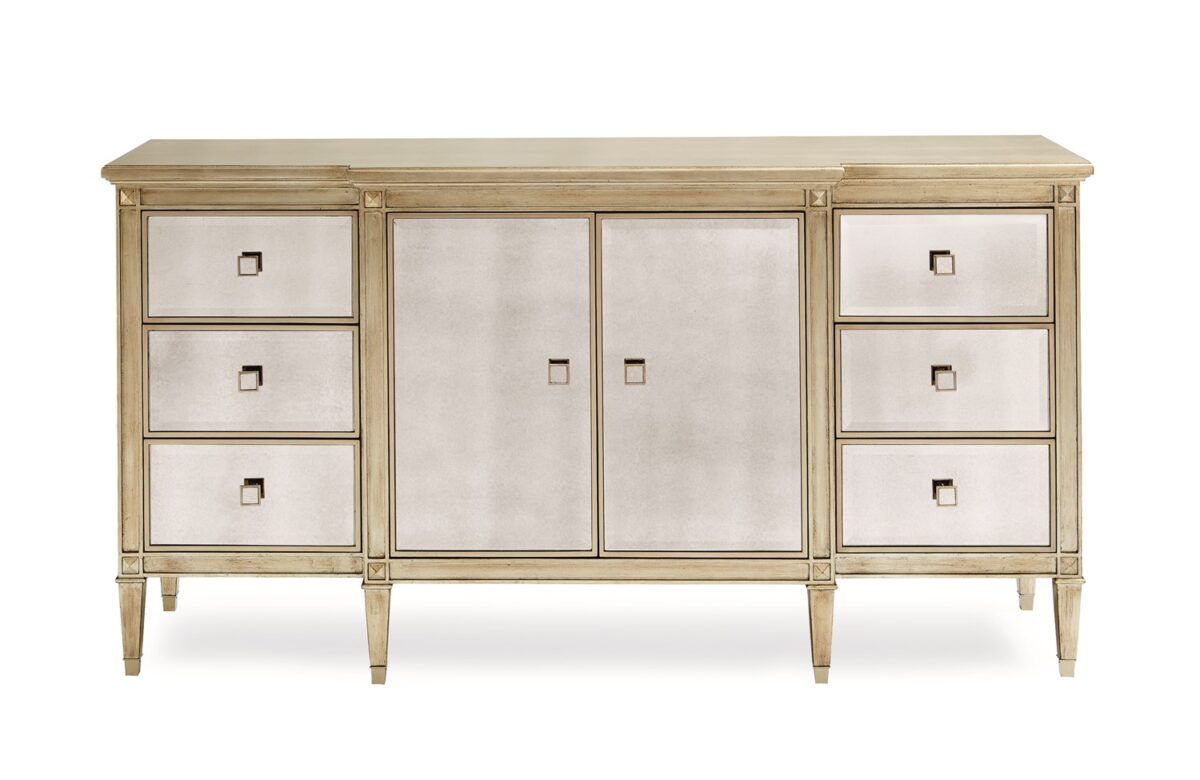 La‑Dee‑Dah Dresser by Caracole — a 74″‑wide carved dresser with six soft‑close side drawers and two mirrored center doors, finished in Auric silver leaf with beveled antique-mirror fronts, square tapered carved feet with metal ferrules, and a gold-painted interior featuring a tray drawer and shelf.