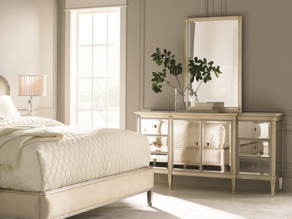 La‑Dee‑Dah Dresser by Caracole — a 74″‑wide carved dresser with six soft‑close side drawers and two mirrored center doors, finished in Auric silver leaf with beveled antique-mirror fronts, square tapered carved feet with metal ferrules, and a gold-painted interior featuring a tray drawer and shelf.