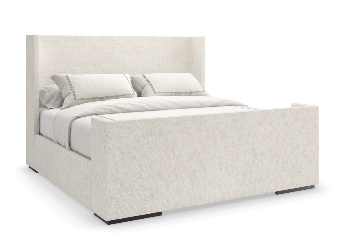 Caracole Shelter Me King Bed featuring a soft chenille upholstered headboard, footboard, and side rails, complemented by decorative buttons and a plinth base in Almost Black finish.