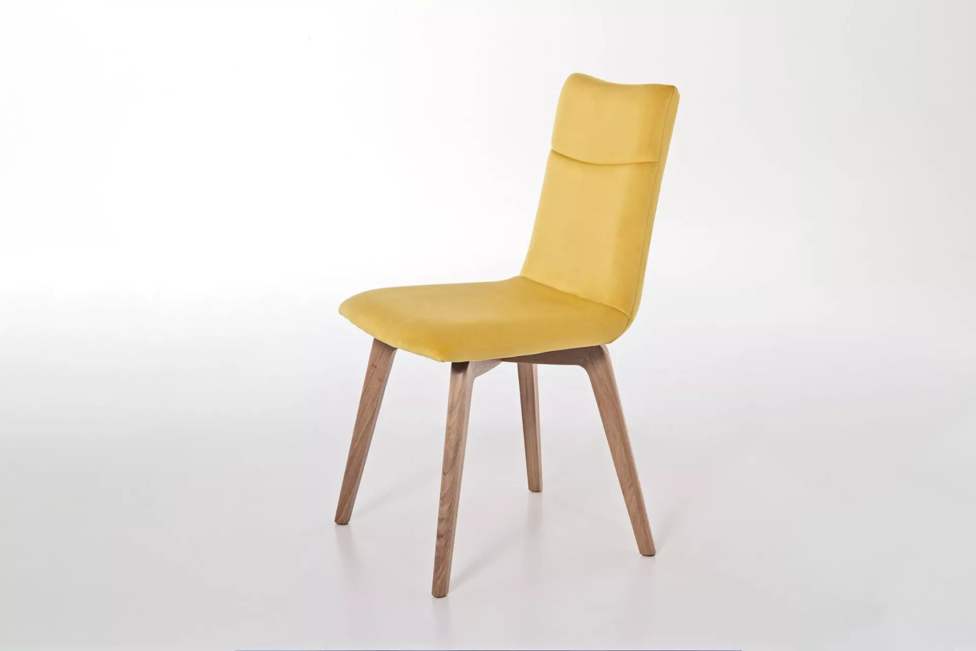 Akila chair in plum velvet with decorative button tuft on the backrest and black four-spoke swivel base, shown on a white studio floor.