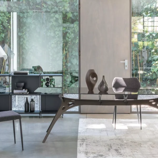 Angle chair by Peressini with sharply slanted backrest and sleek metal legs, upholstered in light grey fabric.